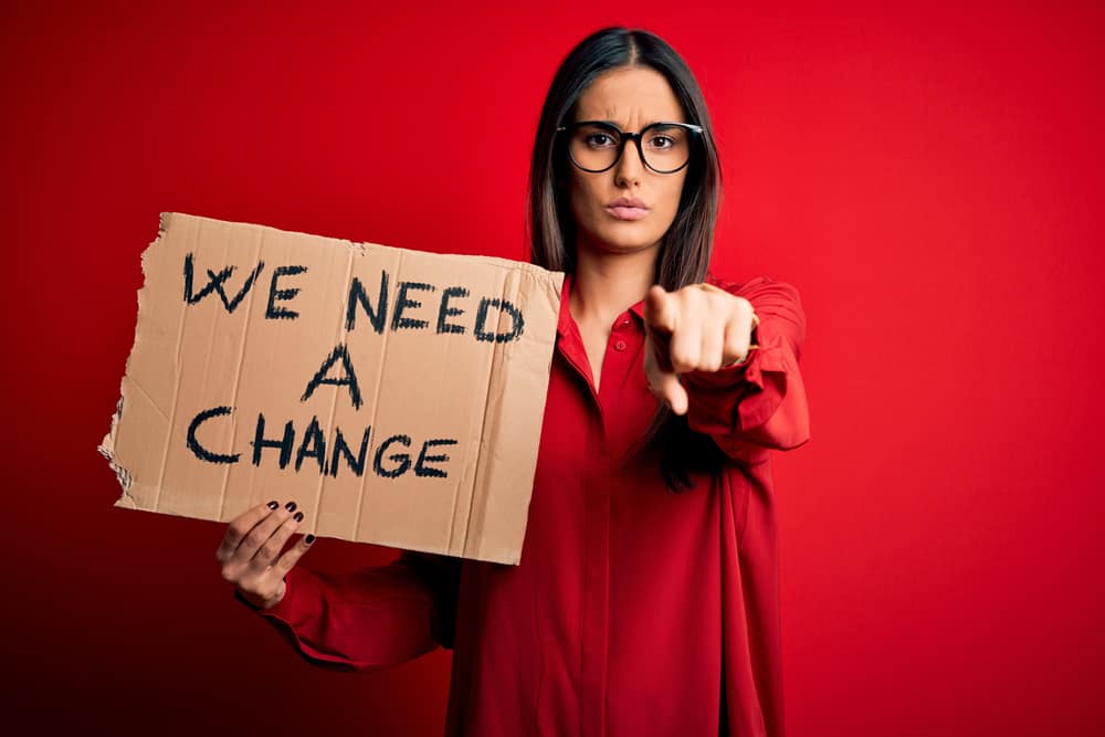 Woman holding a cardboard demanding change Photo credit Everyday Power