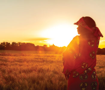 Woman looking over a field in the sunset (Photo credit: Darren Baker/Getty Images)